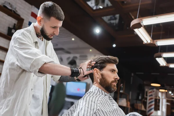 Barbeiro corte de cabelo de cliente morena na barbearia — Fotografia de Stock