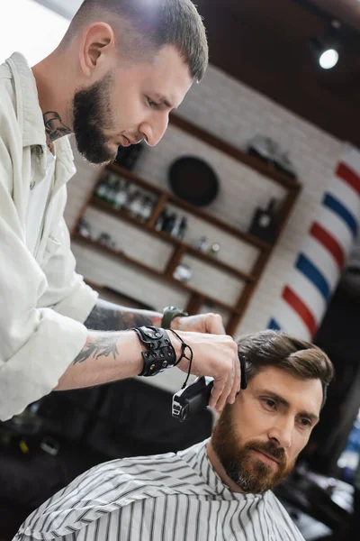 Barbeiro aparar o cabelo do cliente morena na barbearia — Fotografia de Stock