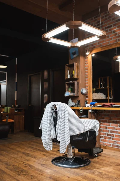 Cape de coiffure sur fauteuil près du plan de travail et miroir salon de coiffure — Photo de stock