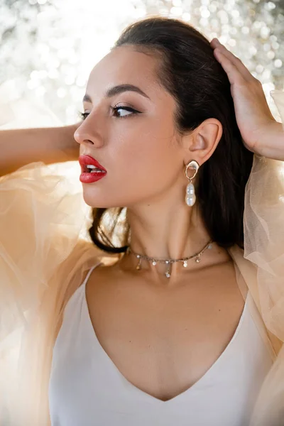 Young glamour woman with red lips touching hair and looking away on shiny background — Stock Photo