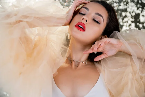 Sexy woman in tulle dress posing with closed eyes on glitter silver background — Stock Photo