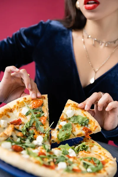 Обрезанный вид стильной женщины рядом с вкусной пиццей изолированы на красный — стоковое фото