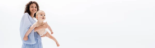 Mujer sonriente en vestido sosteniendo hija bebé aislado en blanco, bandera - foto de stock