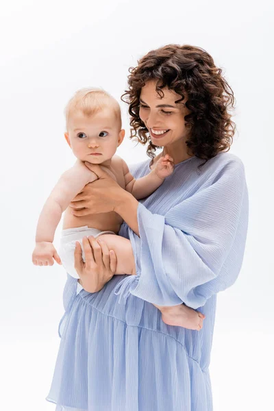 Mujer sonriente en vestido azul tocando niña aislada en blanco - foto de stock