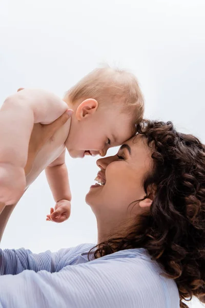 Vue latérale de la mère tenant bébé fille heureuse avec les yeux fermés isolés sur blanc — Photo de stock