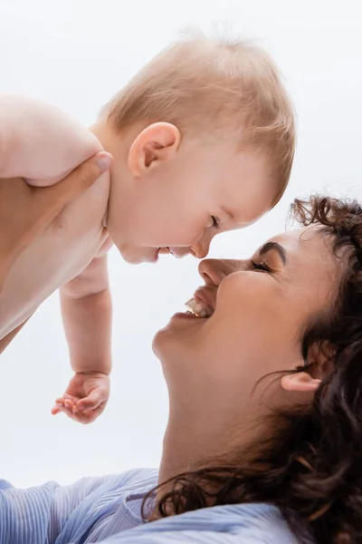 Portrait of positive mother holding baby girl nose to nose isolated on white — Stock Photo