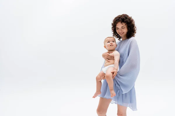 Brünette Frau im Kleid hält Säugling Tochter isoliert auf weiß mit Kopierraum — Stockfoto