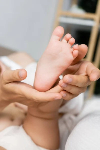 Vista cortada dos pais tocando o pé da filha bebê em casa — Fotografia de Stock