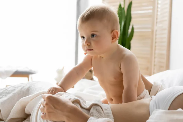 Baby girl sitting near mom on bed in morning — Stock Photo