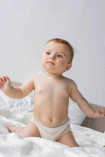 Menina infantil em calcinha sentado na cama de manhã — Fotografia de Stock