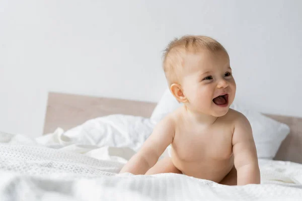 Bébé fille excitée regardant loin sur le lit le matin — Stock Photo