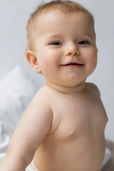 Portrait de bébé fille souriante regardant la caméra sur lit flou — Photo de stock