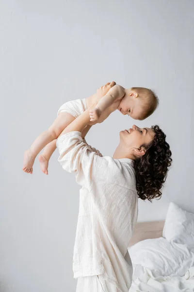 Glückliche Frau im Pyjama spielt mit kleiner Tochter im Schlafzimmer — Stockfoto