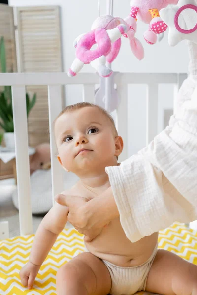 Mother touching infant daughter in crib at home — Stock Photo