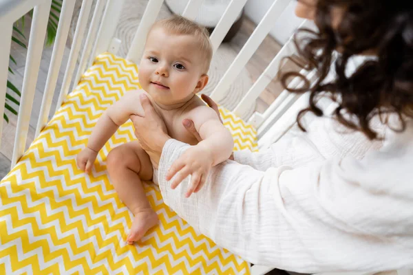 Femme mettant bébé fille dans la crèche à la maison — Photo de stock