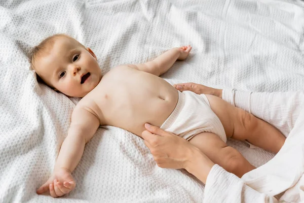 Top view of woman wearing panties on infant daughter on bed — Stock Photo