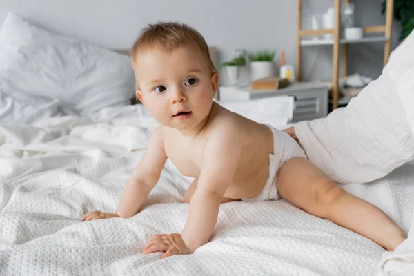 Femme touchant bébé fille en couche sur le lit à la maison — Photo de stock