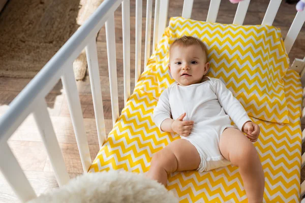 High angle view of baby girl lying in crib in bedroom — Stock Photo