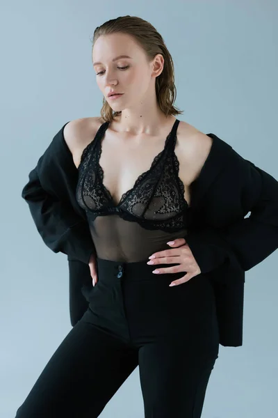 Сексуальная женщина в черном нижнем белье и брюки позируют с руками на бедрах изолированы на сером — стоковое фото