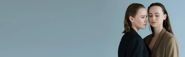 Jolie lesbienne femme en noir blazer près de brunette copine isolé sur gris, bannière — Photo de stock