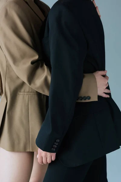 Abgeschnittene Ansicht einer lesbischen Frau, die Freundin im schwarzen Blazer umarmt, isoliert auf grau — Stockfoto