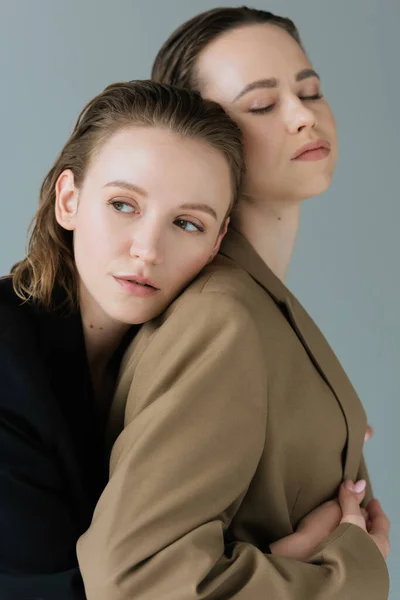 Sensuelle lesbienne femme penché sur jeune copine debout avec les yeux fermés isolé sur gris — Photo de stock