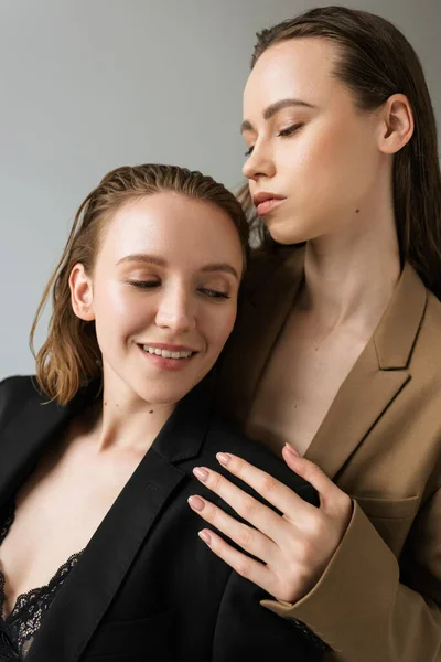 Happy lesbian woman smiling near young brunette girlfriend isolated on grey — Stock Photo