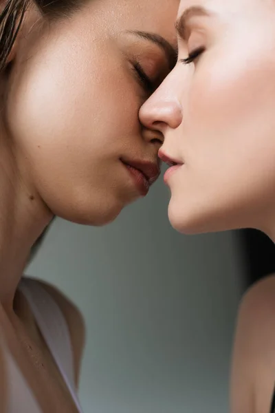 Close up view of young lesbian women kissing isolated on grey — Stock Photo