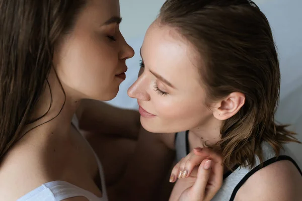 Jeunes et jolies femmes aux yeux fermés posant face à face sur fond gris — Photo de stock