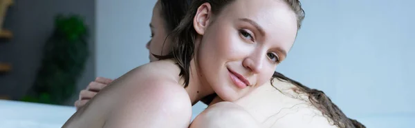 Счастливая молодая женщина обнимает лесбиянку партнера в ванной и смотрит в камеру, баннер — стоковое фото