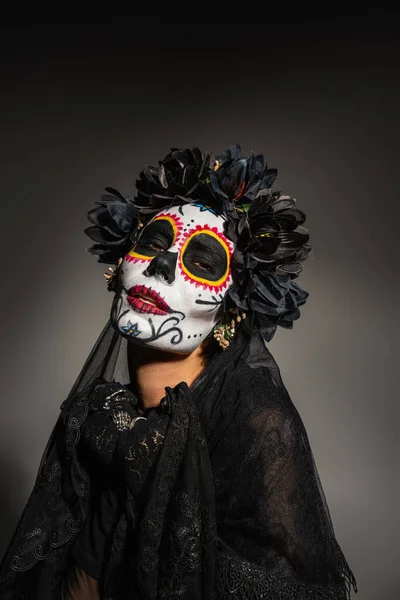 Portrait of woman in mexican day of dead costume looking at camera on black background — Stock Photo