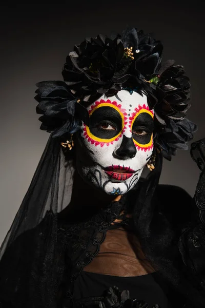 Frau in Catrina-Make-up und Kranz mit dunklem Schleier auf schwarzem Hintergrund — Stockfoto
