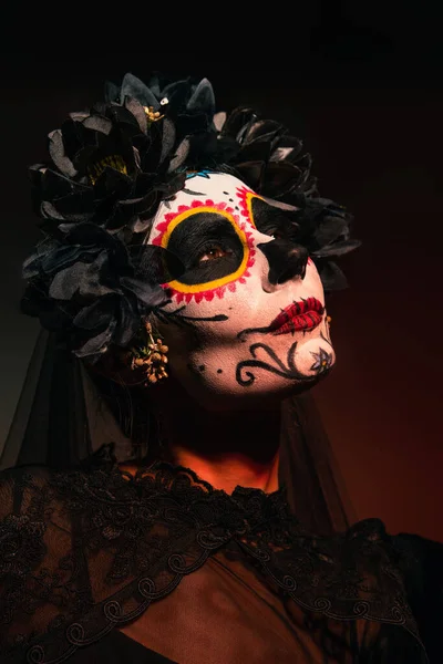 Портрет женщины в мексиканский день мертвого костюма, стоящей на бордовом фоне — стоковое фото