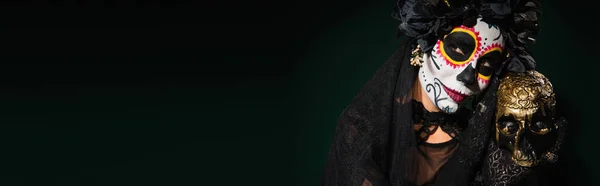 Mulher com dia mexicano de maquiagem morta segurando crânio no fundo verde escuro, banner — Fotografia de Stock