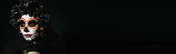 Femme en couronne noire et maquillage du crâne de sucre regardant loin noir sur fond vert foncé, bannière — Photo de stock