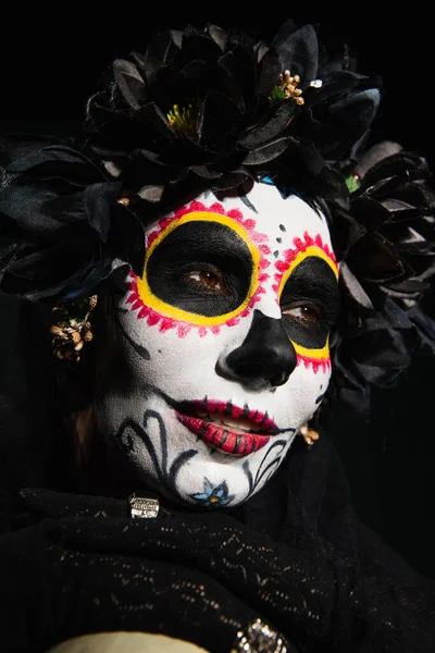Retrato de mujer vestida con traje mexicano de santa muerte mirando hacia otro lado aislado sobre negro - foto de stock