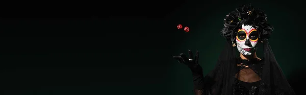 Woman in mexican day of dead costume and makeup throwing dice on dark green background, banner — Stock Photo