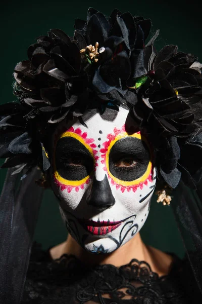 Portrait of woman with catrina makeup and black flowers on wreath isolated on dark green — Stock Photo