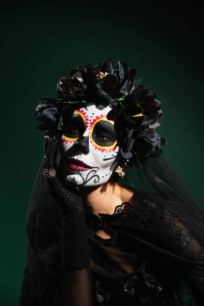 Mujer en el día de la muerte disfraz de Halloween mirando hacia otro lado aislado en verde oscuro - foto de stock