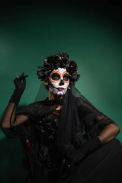 Femme en costume effrayant santa muerte posant sur fond vert — Photo de stock