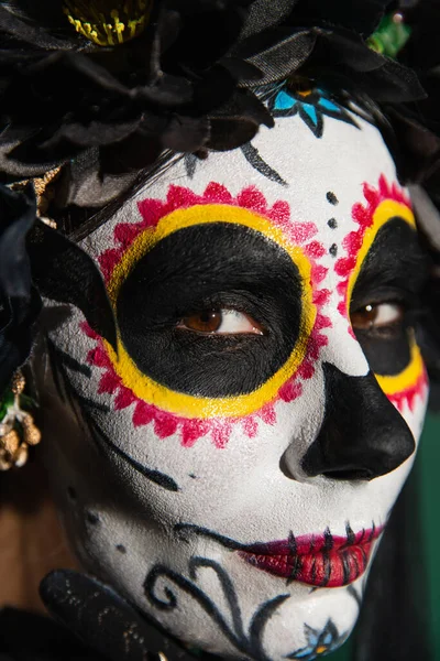 Portrait of woman with day of death makeup looking at camera on green background — Stock Photo