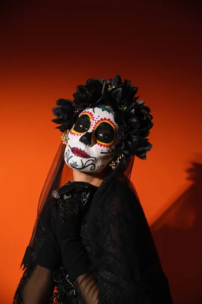 Femme en costume d'Halloween santa muerte regardant la caméra sur fond rouge — Photo de stock