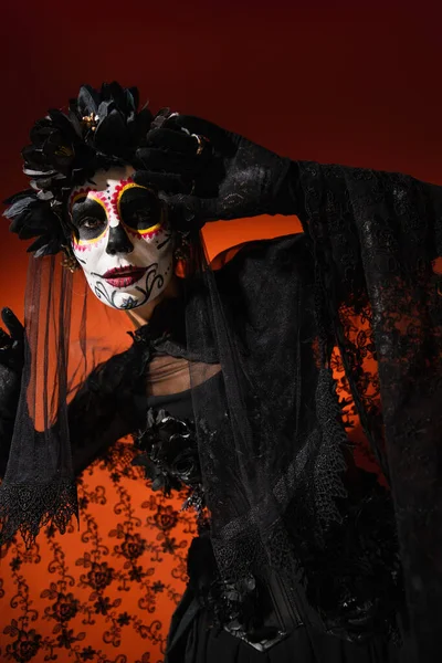 Donna in costume messicano Santa Muerte posa su sfondo rosso — Foto stock