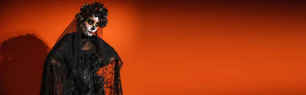 Donna in costume di Halloween nero e trucco raccapricciante su sfondo arancione con ombra scura, banner — Foto stock