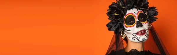 Retrato de la mujer sonriente en el maquillaje de Halloween espeluznante y corona negra aislada en naranja, bandera - foto de stock