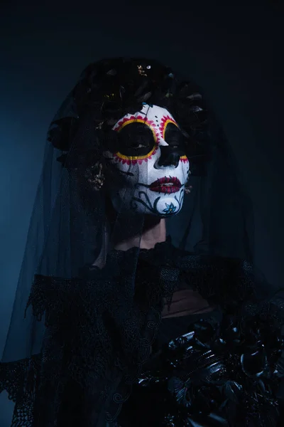 Frau in traditionellem mexikanischen Catrina-Make-up und schwarzem Kranz mit Schleier auf dunkelblauem Hintergrund — Stockfoto