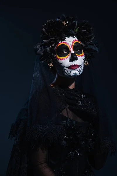 Femme dans le maquillage effrayant halloween et costume noir de sorcière sur fond sombre — Photo de stock
