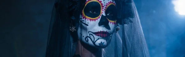 Retrato de mujer en halloween azúcar cráneo maquillaje y velo sobre fondo oscuro con luz azul, bandera - foto de stock