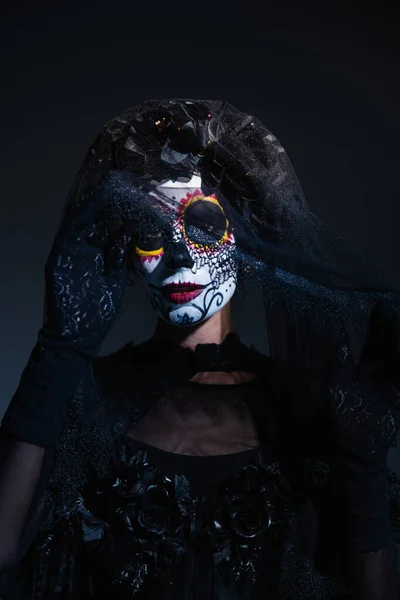 Retrato de mujer en espeluznante maquillaje de halloween y corona negra con velo de encaje sobre fondo oscuro - foto de stock