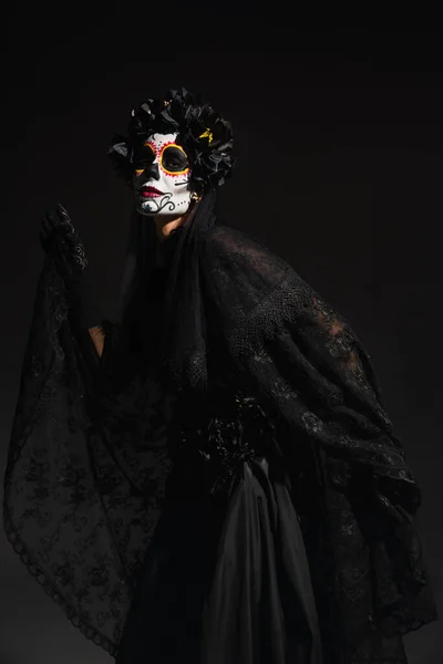 Mujer en traje de bruja oscura y espeluznante maquillaje de Halloween posando aislado en negro - foto de stock